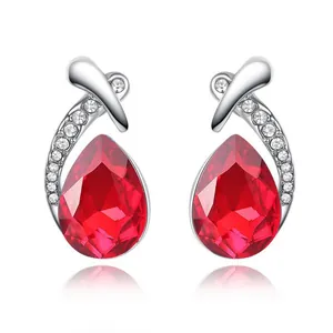 Detail of silver stud earrings featuring a red teardrop crystal and pavé accents