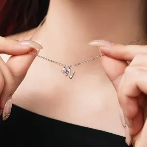 Close-up detail shot of a silver letter N pendant necklace with a small crystal charm.