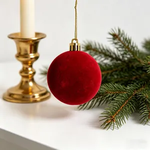 Primo piano di una palla di Natale rossa floccata con cappuccio dorato su sfondo festivo