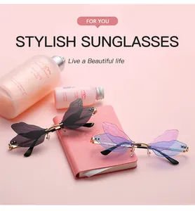 Stylish dragonfly wing shaped sunglasses displayed with pink aesthetic props in a studio setting