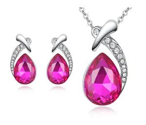 Close-up of fuchsia teardrop crystal necklace and earrings set in polished silver