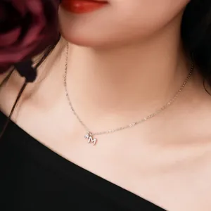 Close-up view of S925 sterling silver necklace with dainty letter M pendant worn by model