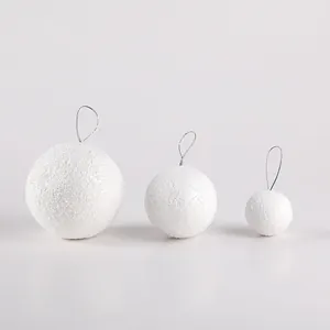 Primo piano di tre palline di neve in schiuma bianca di varie dimensioni con ganci argento
