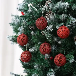 Palline di Natale rosse glitterate traforate appese a un abete per decorazione festiva