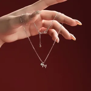 Close-up detail of S925 sterling silver necklace featuring a minimalist letter M pendant