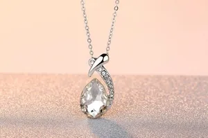 Detailed macro shot of an elegant waterdrop crystal pendant necklace on a silver chain