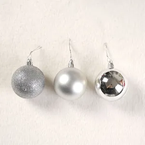 Dettaglio di tre palline di Natale argento con finiture glitterate, opache e lucide