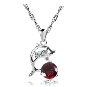 Detailed shot of a silver dolphin pendant necklace featuring a large red crystal