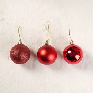 Vista dettagliata di palline di Natale rosse con texture glitterate, opache e lucide.