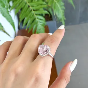 Gros plan exquis d'une bague en zircone rose en forme de cœur sur le doigt d'une femme élégante