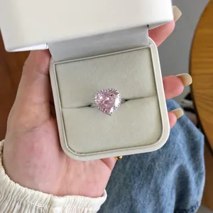 Gros plan d'une bague en zircon rose en forme de cœur dans un élégant écrin blanc à bijoux.