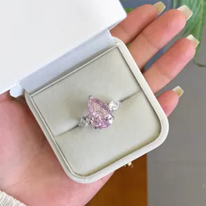 Gros plan d'une bague en zircon rose dans son écrin blanc élégant tenu à la main