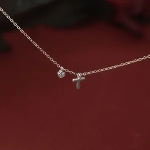 Macro view of silver necklace with matte letter T and sparkling zircon pendant.
