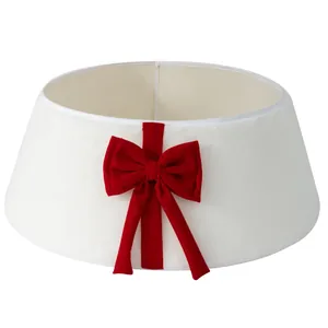 Elegant white plush Christmas tree collar featuring a large red velvet bow decoration