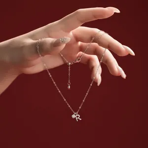 Close-up of an elegant S925 sterling silver necklace with a letter R pendant detail.