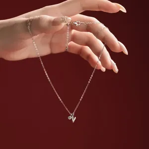 Close-up of sterling silver necklace with letter V pendant and small crystal charm.