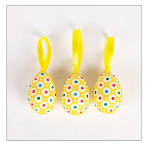 Detailed view of three yellow fabric-wrapped Easter egg hanging ornaments
