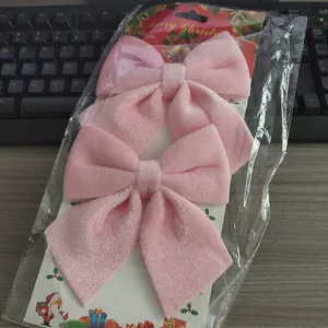 Detailweergave van twee roze fluwelen kerststrikken in de originele verpakking op bureau