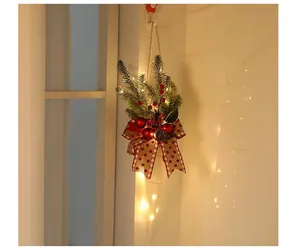 Detail of lighted Christmas cone ornament with pine needles and red bow.
