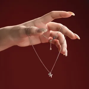 Close-up of a dainty S925 sterling silver necklace with a small letter pendant on a hand