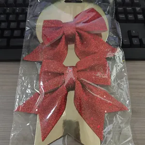 Primer plano de lazos navideños rojos con purpurina en bolsa de plástico transparente.