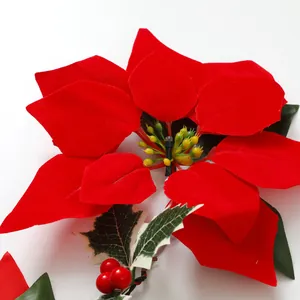 Nahaufnahme einer roten Weihnachtsstern-Blume mit LED und Stechpalmenbeeren.