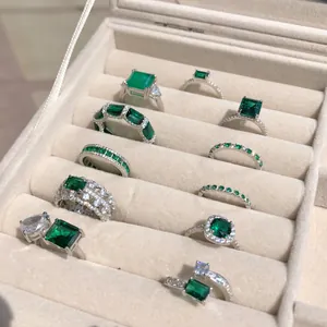 Collezione dettagliata di anelli vintage verde smeraldo in un vassoio portagioie beige.