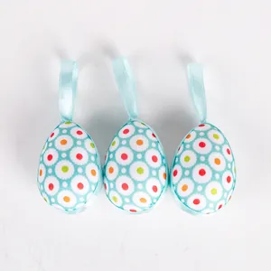 Trio of decorative fabric-wrapped Easter eggs with colorful dot patterns and hanging ribbons