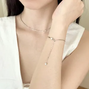 Detalle de collar minimalista de plata S925 y pulsera ajustable con dije en una modelo