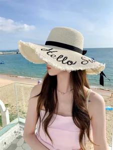 Κοντινό πλάνο ψάθινου καπέλου με κέντημα 'Hello Sun' και μεγάλο γείσο για την παραλία.