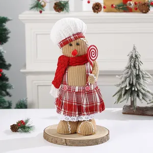 Handcrafted gingerbread doll ornament standing on a wooden base in a Christmas scene