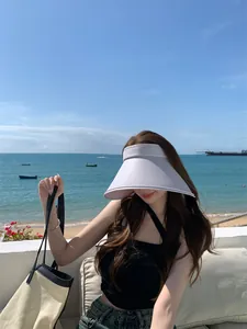 Aziatische vrouw met een stijlvolle zonneklep met brede rand op een zonnig strand
