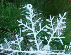 Primo piano di un fiocco di neve in plastica bianca appeso a rami di alberi di Natale