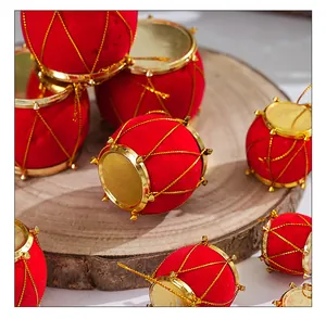 Vista detallada de adornos de tambor navideño rojos flocados sobre una base de madera rústica