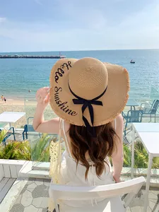 Ψάθινο καπέλο με πλατύ γείσο και κέντημα 'Hello Sunshine' σε βεράντα παραλίας
