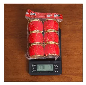 Detalle de seis mini tambores navideños rojos flocados en una báscula que pesa 47,4 g