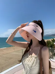 Gedetailleerd overzicht van een vrouw met een stijlvolle roze zonnehoed op het strand