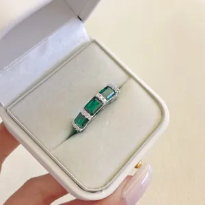 Primo piano di anello in argento S925 con pietre verdi taglio smeraldo in confezione regalo.