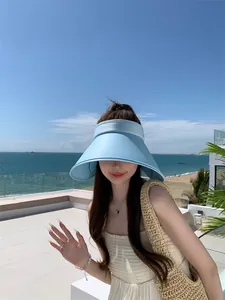 Close-up van een vrouw die een lichtblauwe zonneklep met brede rand draagt op het strand