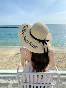 Κοντινό πλάνο ψάθινου καπέλου με κέντημα Hello Sunshine και μαύρη κορδέλα φιόγκο