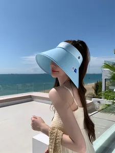 Aziatisch model met een lichtblauwe zonneklep op een zonnig balkon aan de kustlijn