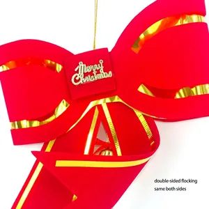 Close-up of a large red flocked Christmas bow decoration with gold Merry Christmas tag