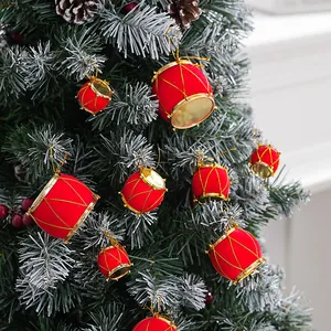 Pequeños tambores rojos flocados colgados en una rama de un árbol de Navidad nevado