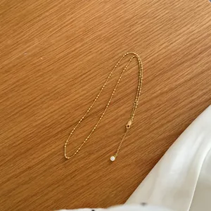Primer plano de un elegante collar de bolas de plata S925 bañado en oro con colgante.