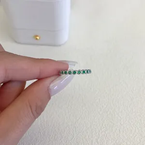 Dettaglio macro di un anello in argento sterling S925 con zirconi verdi tenuto in mano