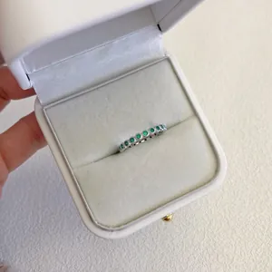 Primo piano di un anello in argento S925 con zirconi verdi smeraldo in un astuccio bianco