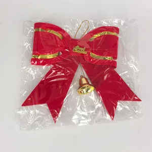 Red velvet Christmas bow with gold bell detail inside transparent plastic packaging.