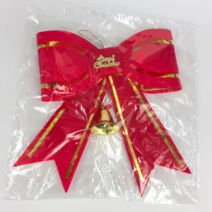 Detailed view of red Christmas bow with gold trim and bell in plastic packaging