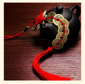 Detailed view of Chinese knot tassel with five emperor coins on a dark teapot