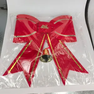 Detail of a large red velvet Christmas bow with gold bell and Merry Christmas text.